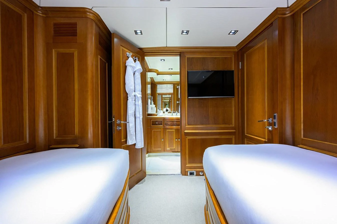 The guest cabin features twin beds, warm wood paneling, and an en-suite bathroom. aboard BENETTI CLASSIC Yacht for Sale