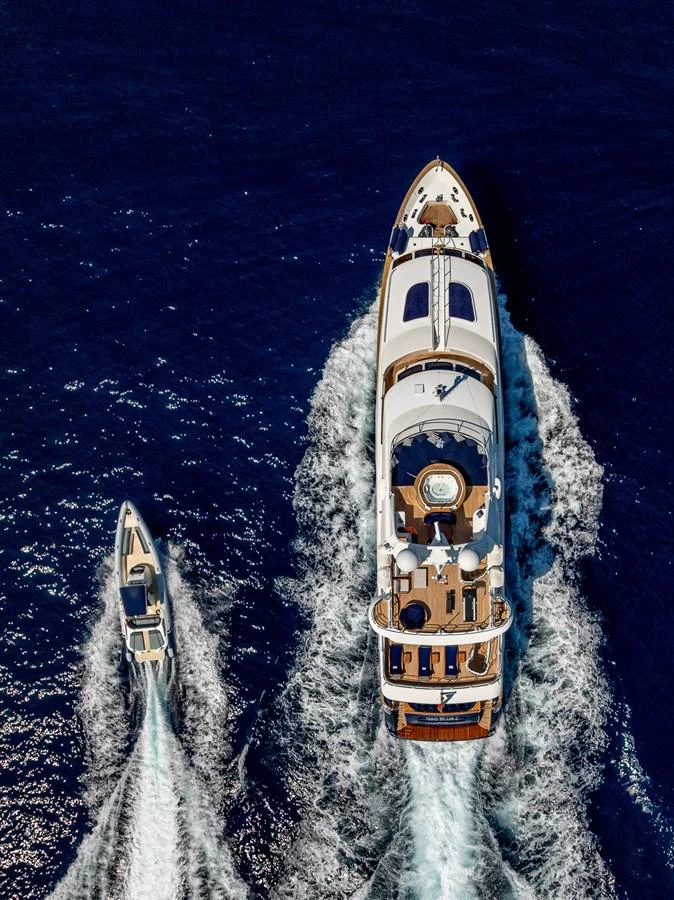 Aerial view of a luxurious yacht cruising on the open sea with a smaller tender alongside. aboard SEA BLUEZ Yacht for Sale