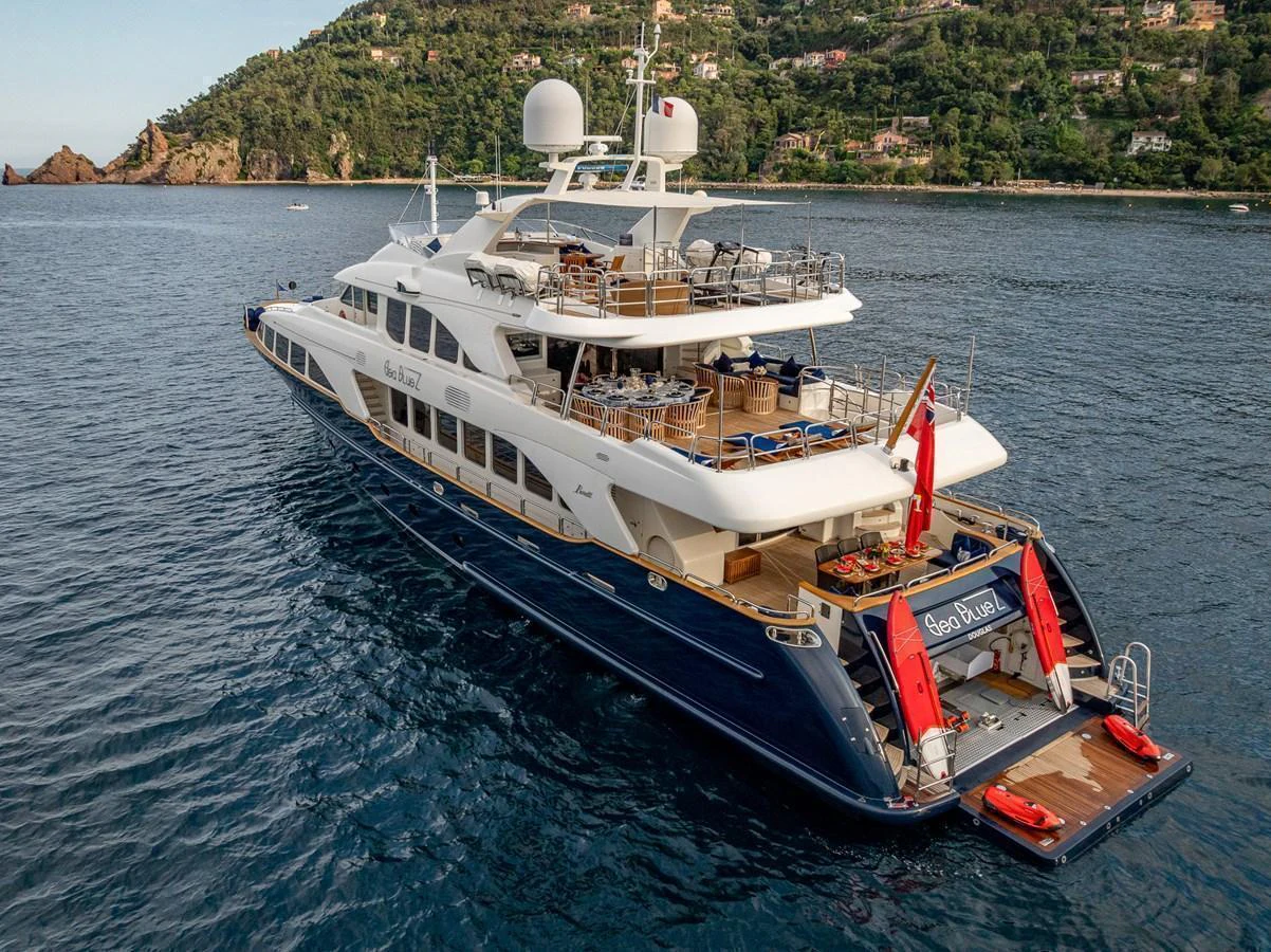 The yacht is elegantly anchored near a lush coastline, showcasing its spacious aft deck and luxurious amenities. aboard SEA BLUEZ Yacht for Sale