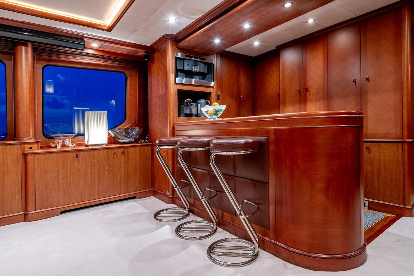 The yacht's galley features rich wooden cabinetry and a sleek bar area with modern bar stools. aboard SEA BLUEZ Yacht for Sale