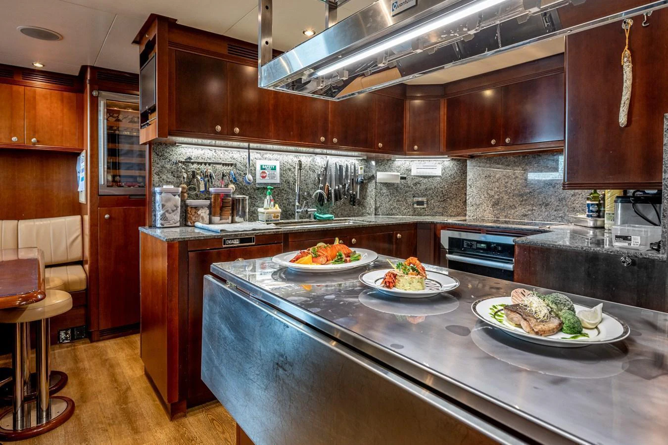 The yacht's galley features rich wooden cabinetry, stainless steel appliances, and a polished countertop with gourmet dishes ready to be served. aboard SEA BLUEZ Yacht for Sale