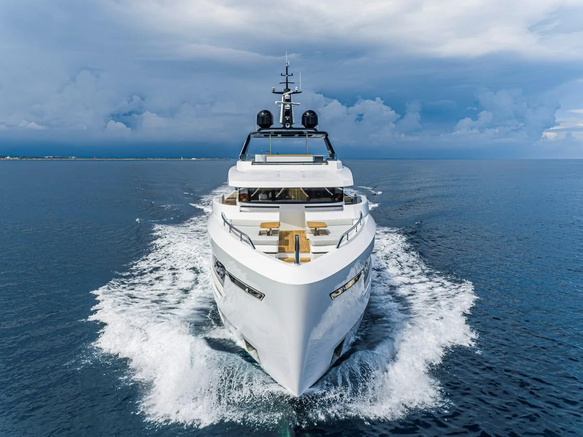 A sleek yacht cruises forward on calm waters under a dramatic sky. aboard DUCALE 120 Yacht for Sale