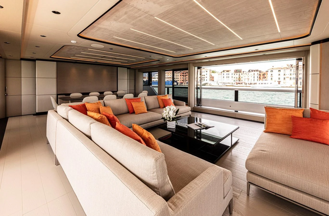 The spacious salon features luxurious seating with vibrant orange accents and panoramic views of the water. aboard DUCALE 120 Yacht for Sale