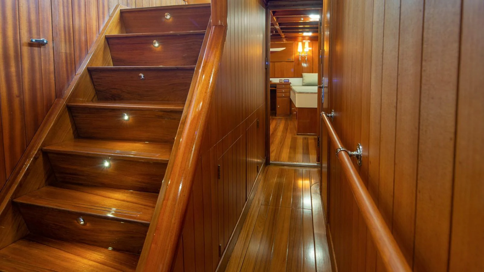 The image showcases a beautifully crafted wooden staircase leading to a cozy interior space. aboard CANDIDA Yacht for Sale