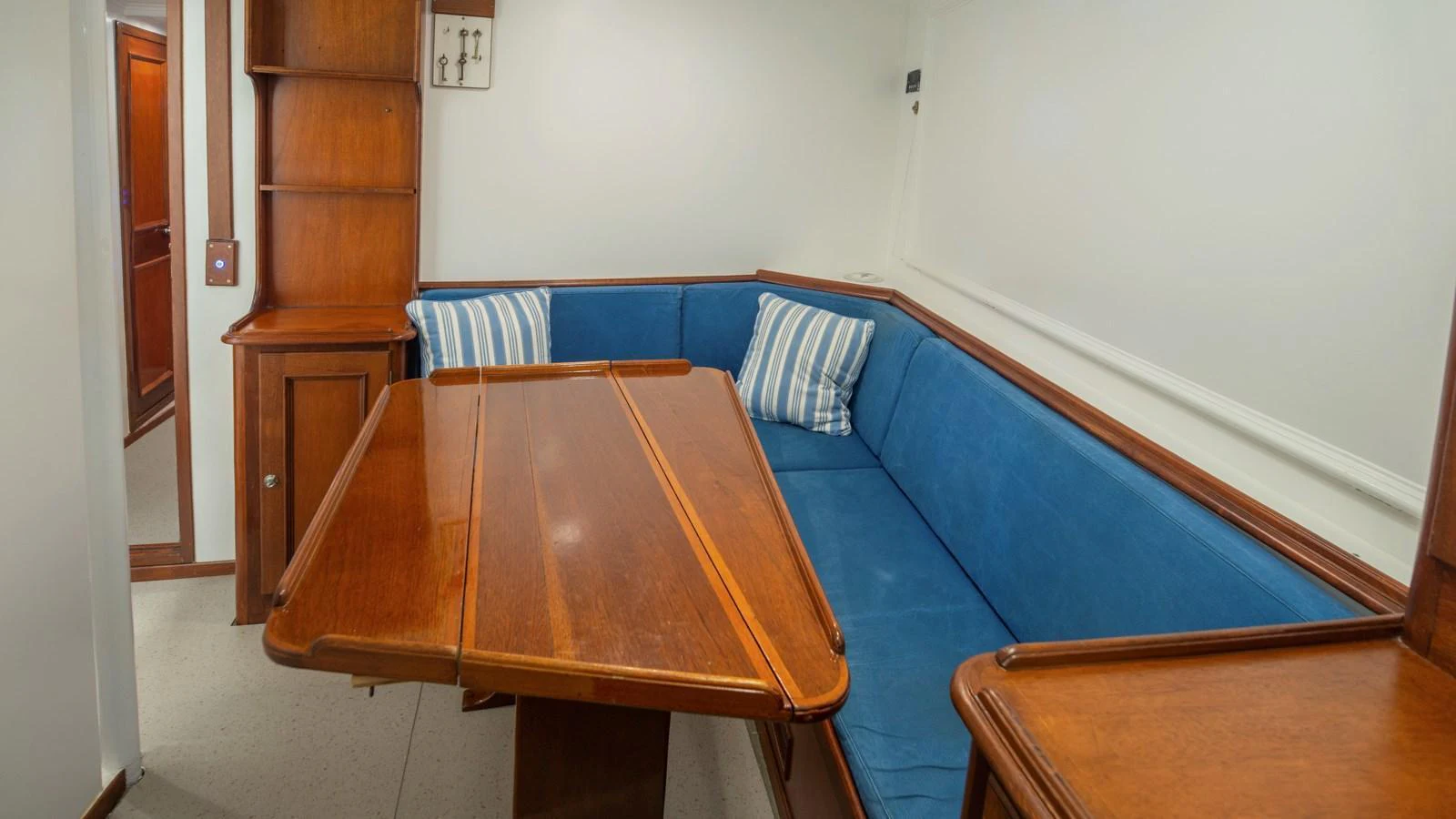 The yacht's dining area features a cozy wooden table and comfortable blue seating with striped cushions. aboard CANDIDA Yacht for Sale