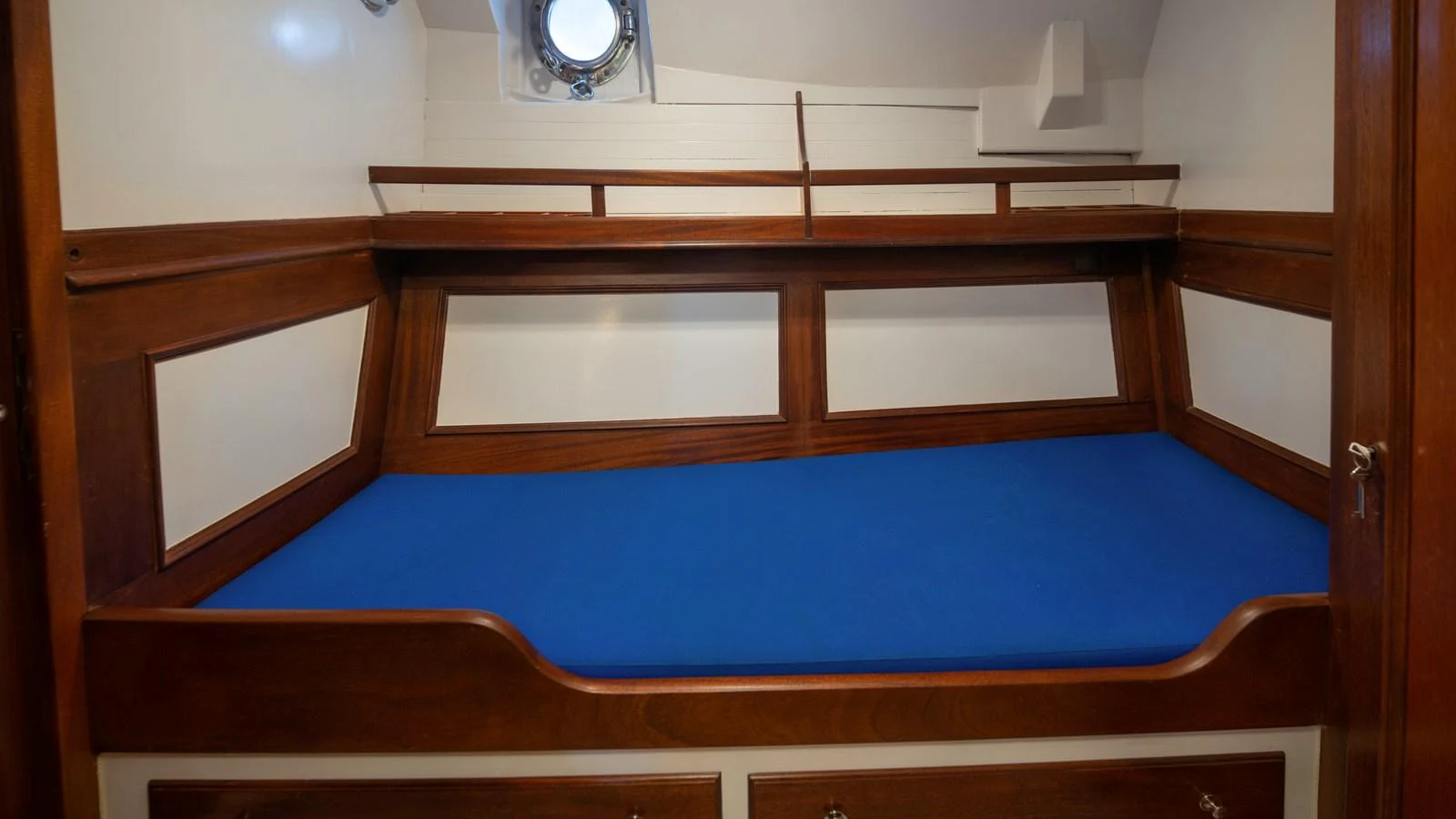 A cozy cabin featuring a blue mattress and wooden accents. aboard CANDIDA Yacht for Sale