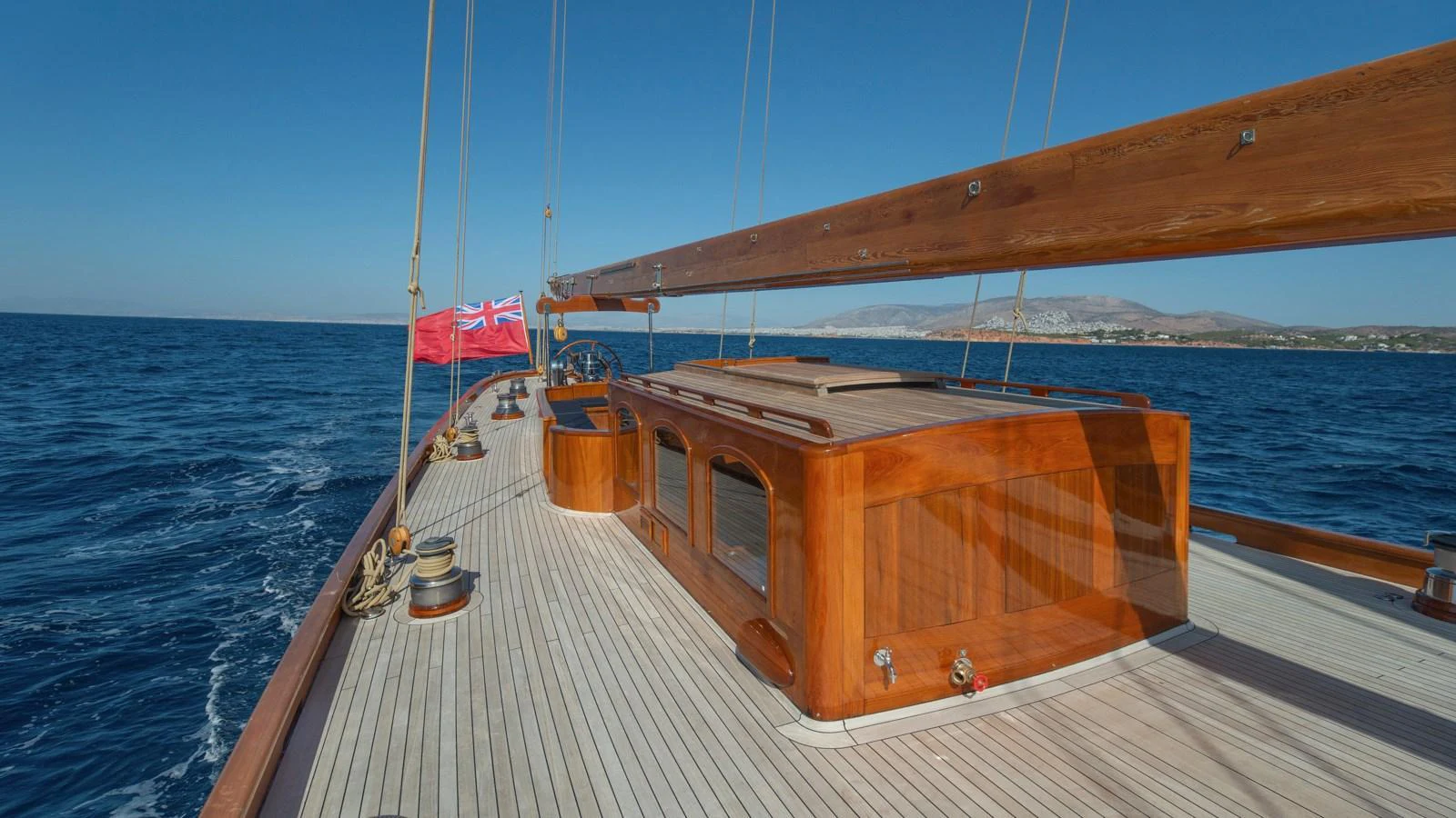 The yacht's deck showcases elegant wooden finishes and a spacious layout under clear blue skies. aboard CANDIDA Yacht for Sale