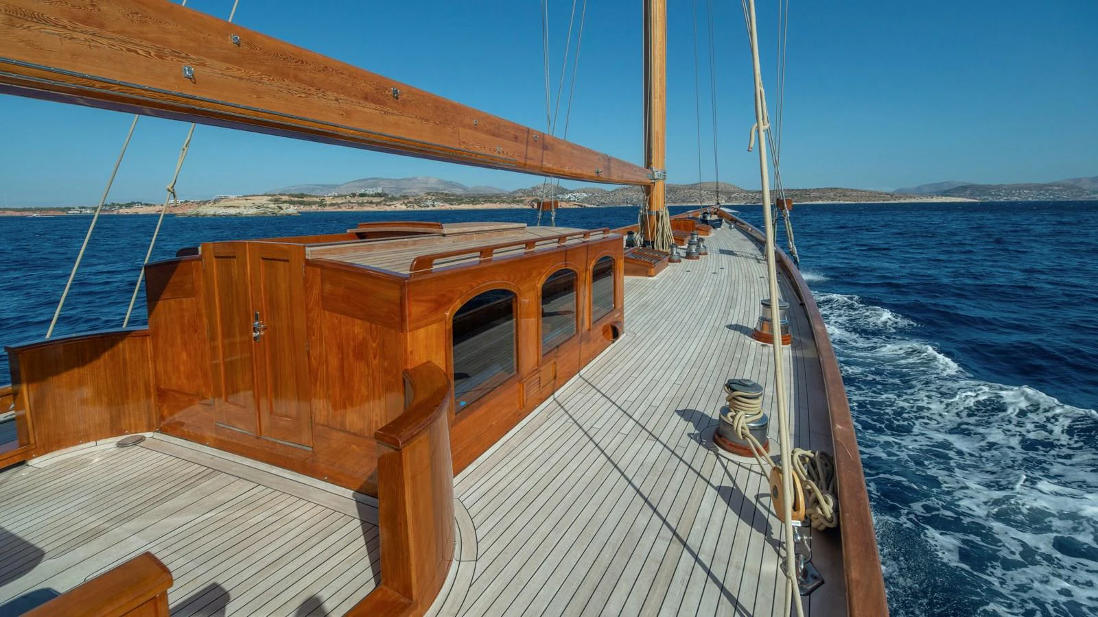 A beautifully crafted wooden deck of a sailing yacht gliding through the open sea. aboard CANDIDA Yacht for Sale