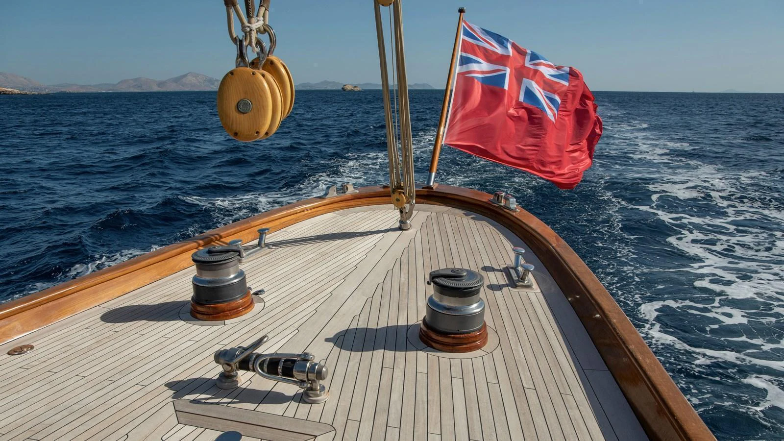 The yacht's deck features a classic design with a prominent flag waving at the stern. aboard CANDIDA Yacht for Sale