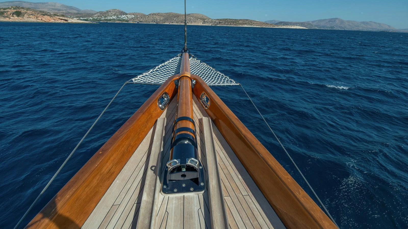 The yacht's bow cuts gracefully through the deep blue waters, showcasing its elegant wooden deck and sleek design. aboard CANDIDA Yacht for Sale