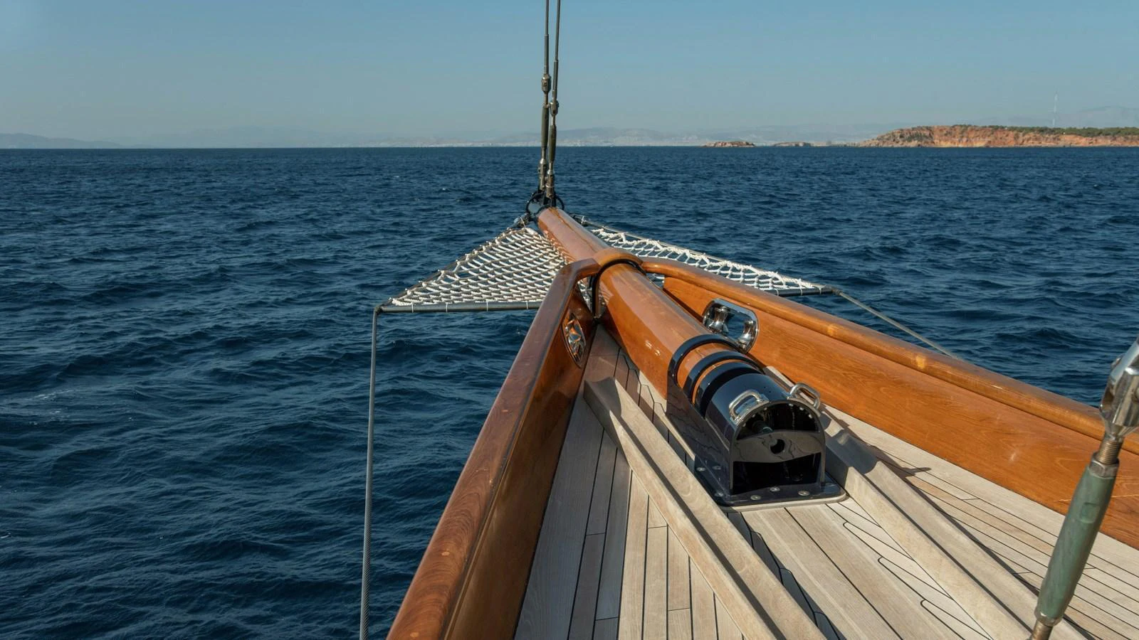 The image showcases the bow of a yacht with a wooden deck and a netting area extending forward. aboard CANDIDA Yacht for Sale