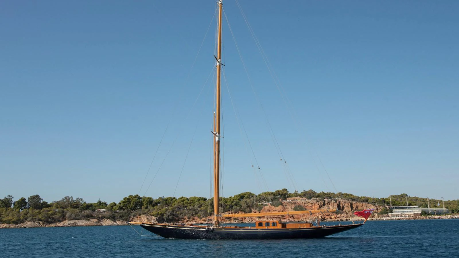 A sleek sailing yacht glides gracefully on calm waters with a scenic coastal backdrop. aboard CANDIDA Yacht for Sale