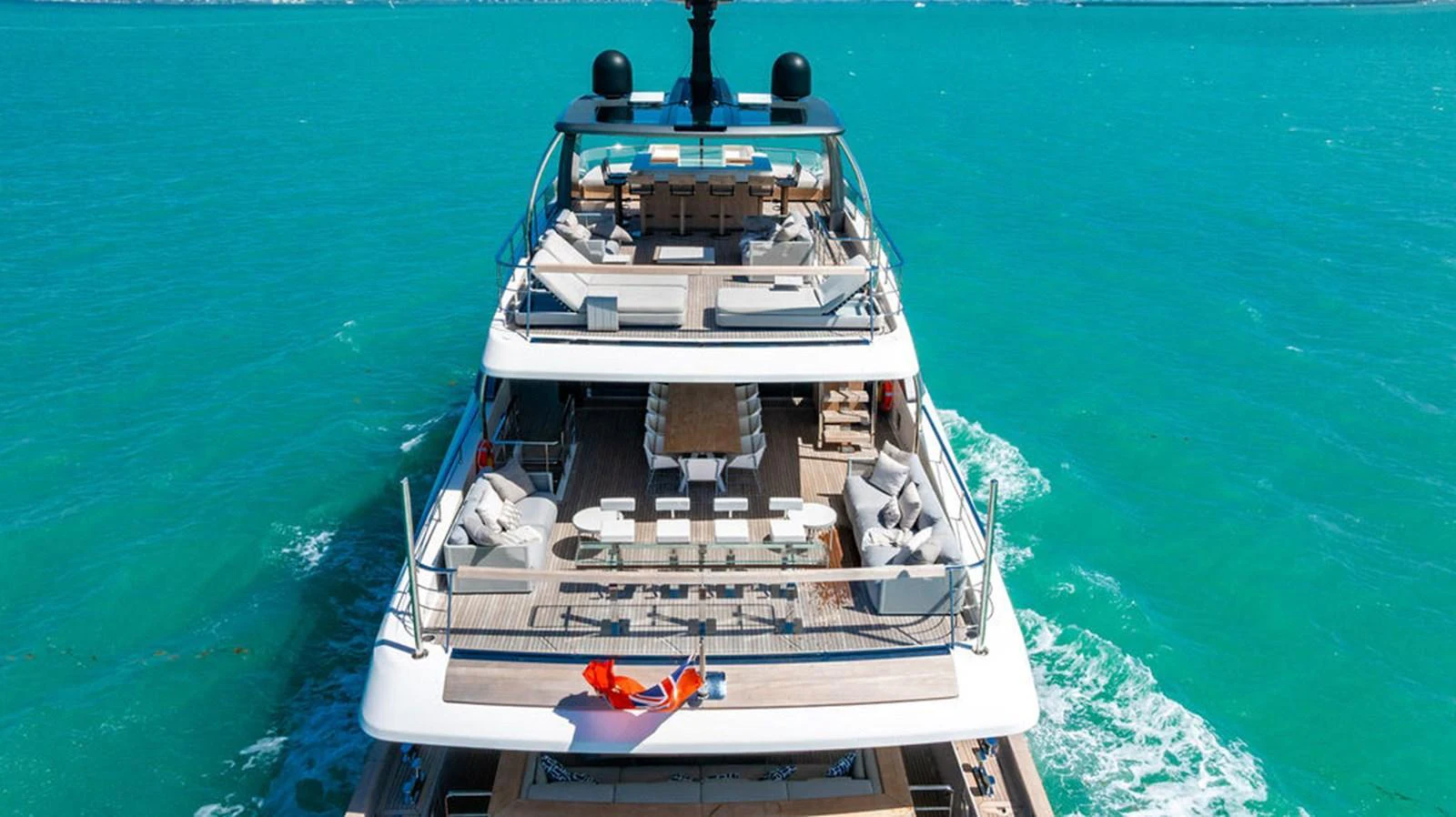A luxurious yacht cruising on turquoise waters, showcasing its spacious aft deck with multiple lounging and dining areas. aboard SANLORENZO SD118/129 Yacht for Sale