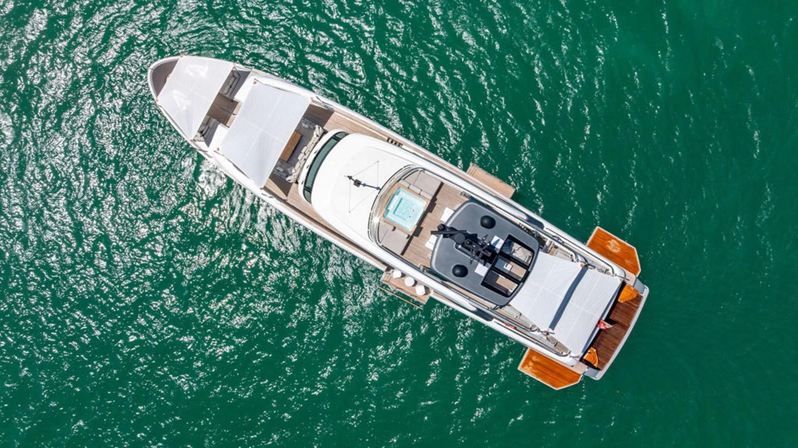 A stunning aerial view of a sleek yacht cruising on clear green waters. aboard SANLORENZO SD118/129 Yacht for Sale