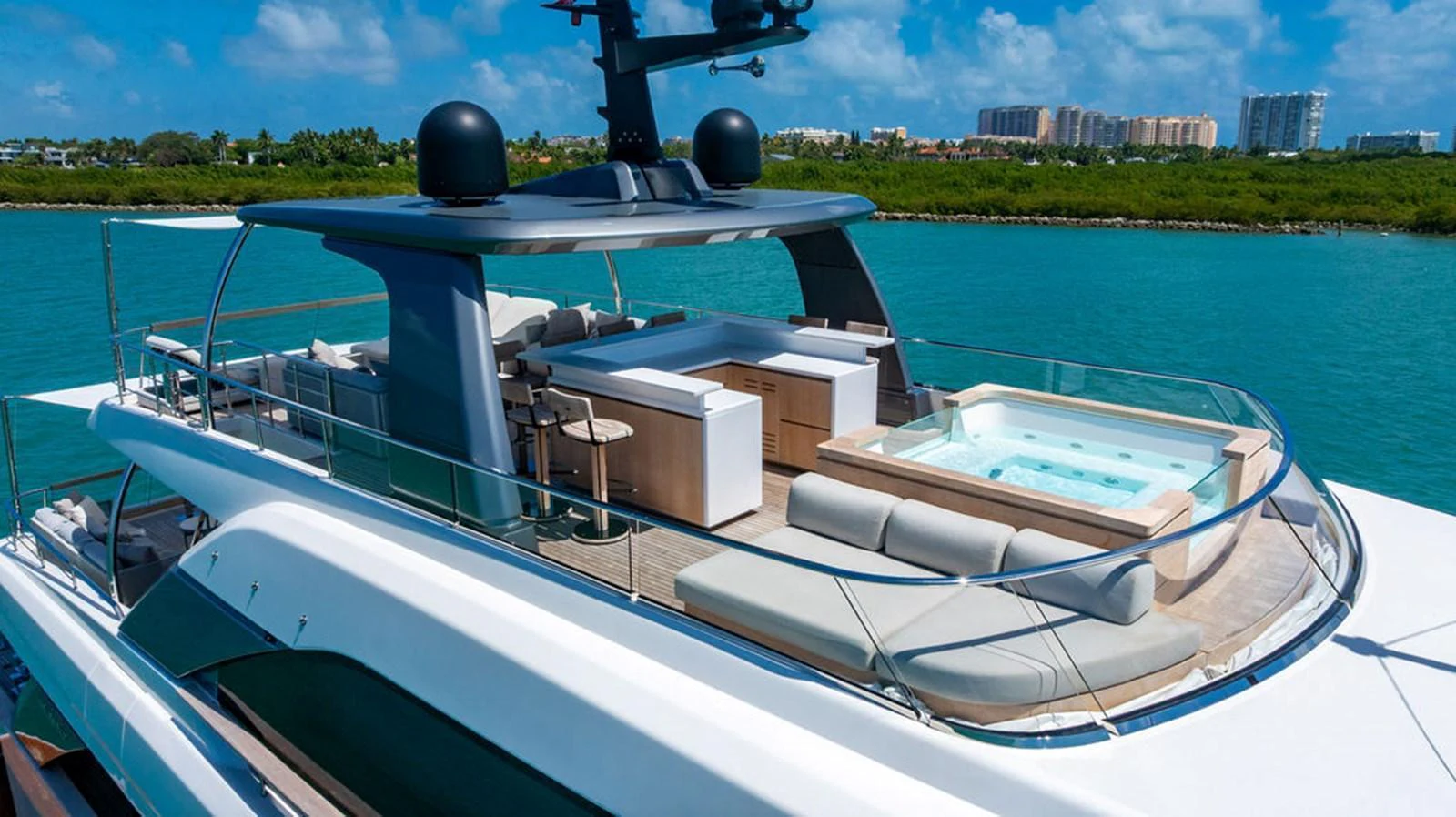 The yacht's flybridge features a luxurious seating area, a bar, and a jacuzzi, all set against a stunning coastal backdrop. aboard SANLORENZO SD118/129 Yacht for Sale