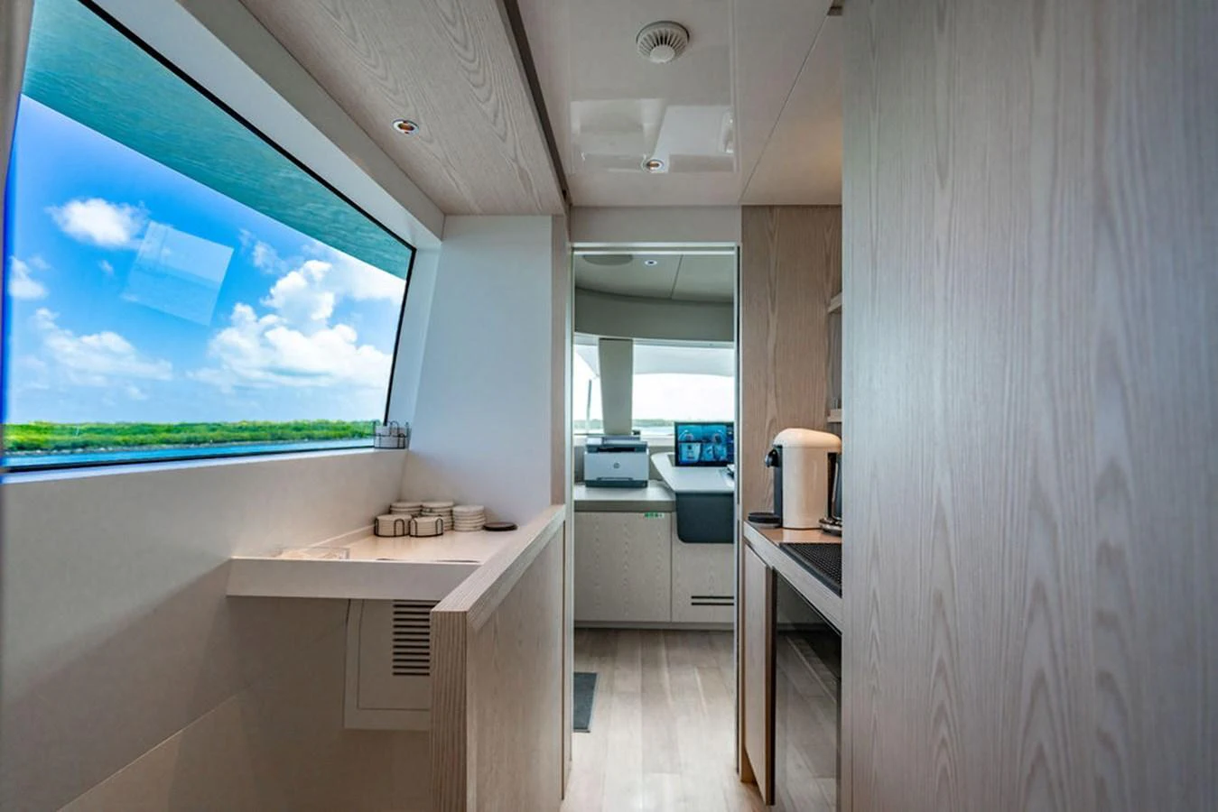 A modern yacht interior with sleek wooden finishes and large windows offering scenic views. aboard SANLORENZO SD118/129 Yacht for Sale