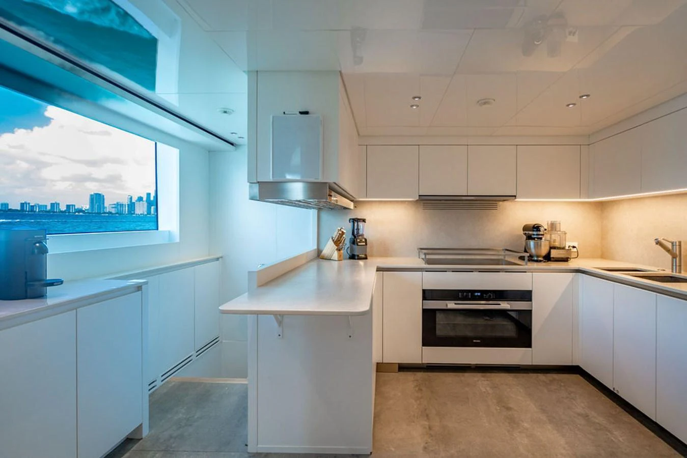 The yacht's galley is modern and well-equipped, featuring sleek white cabinetry and a large window with a city view. aboard SANLORENZO SD118/129 Yacht for Sale