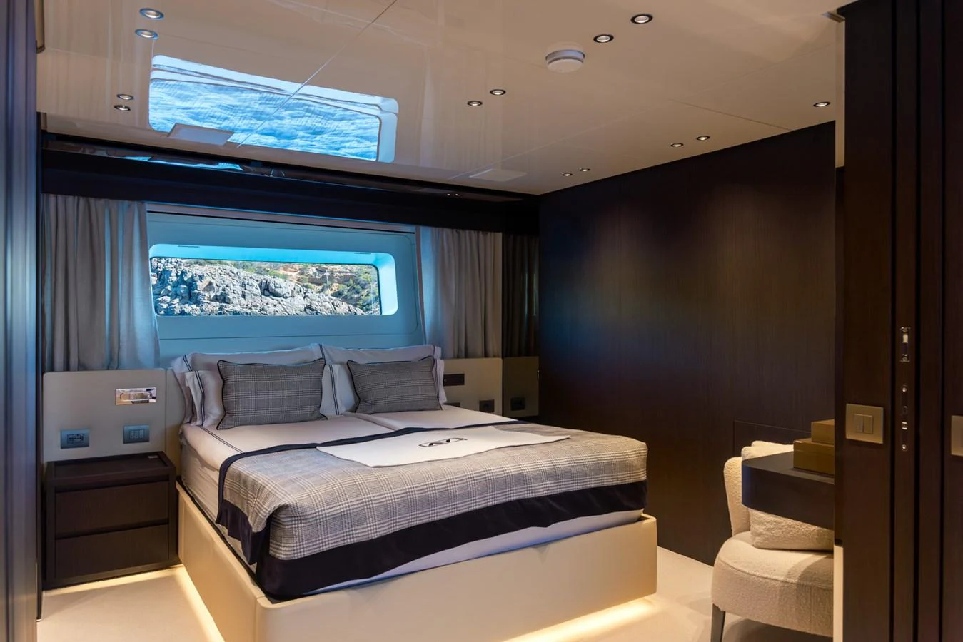 A luxurious stateroom with a large bed, modern lighting, and a scenic window view. aboard AV1 Yacht for Sale