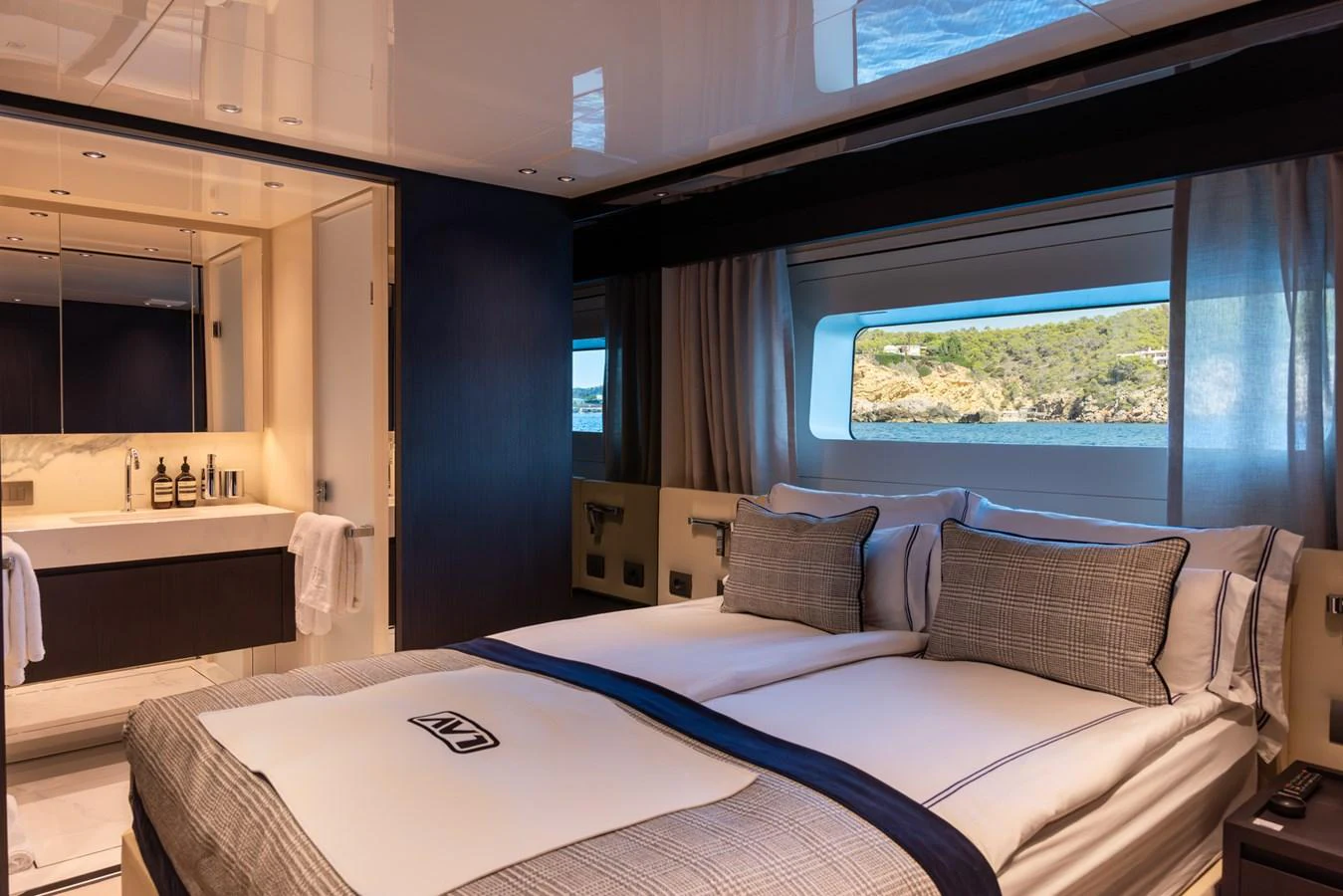 The guest stateroom offers a serene retreat with plush bedding and a scenic view through the large window. aboard AV1 Yacht for Sale