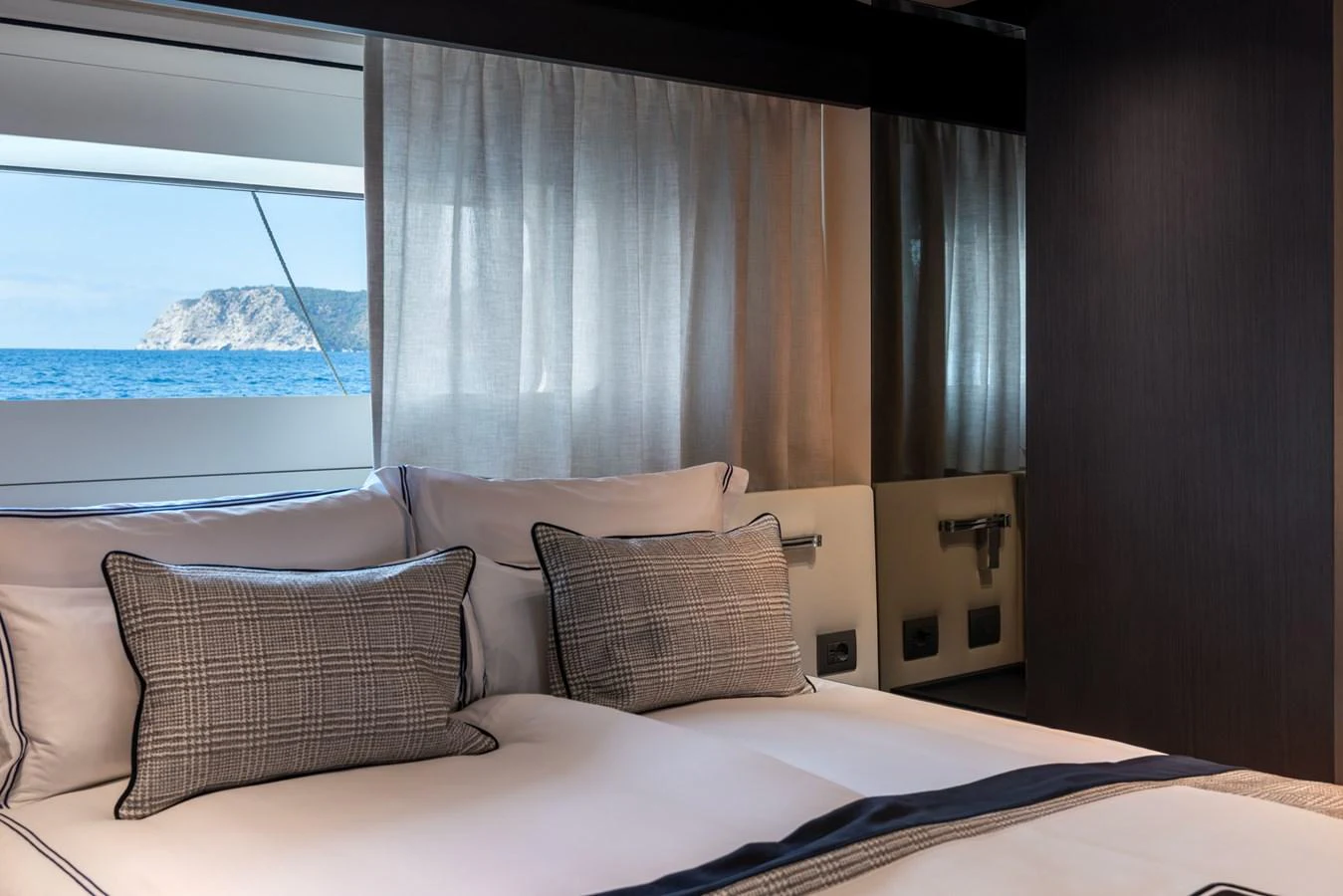 A luxurious stateroom with a large bed and a scenic ocean view through the window. aboard AV1 Yacht for Sale