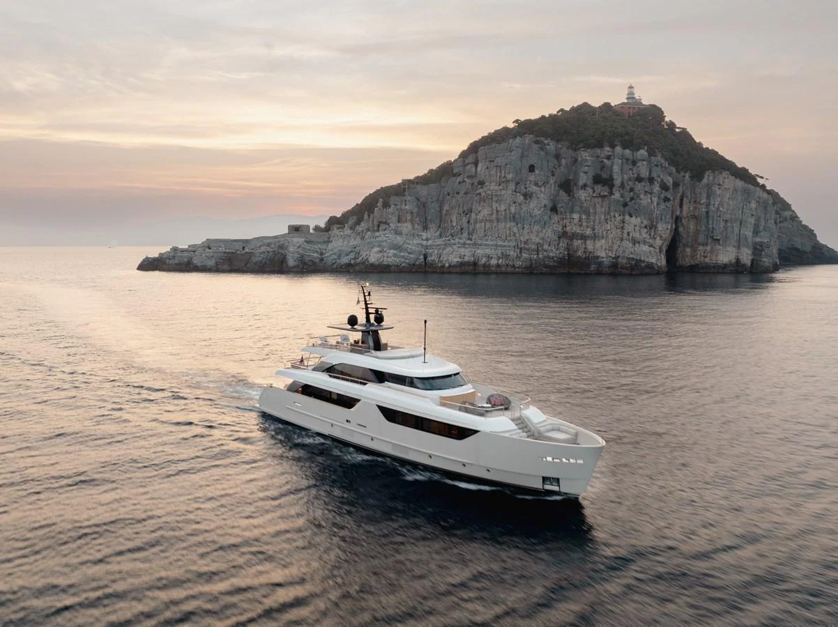 A luxurious yacht cruises gracefully on calm waters with a picturesque island in the background. aboard LET IT BE Yacht for Sale