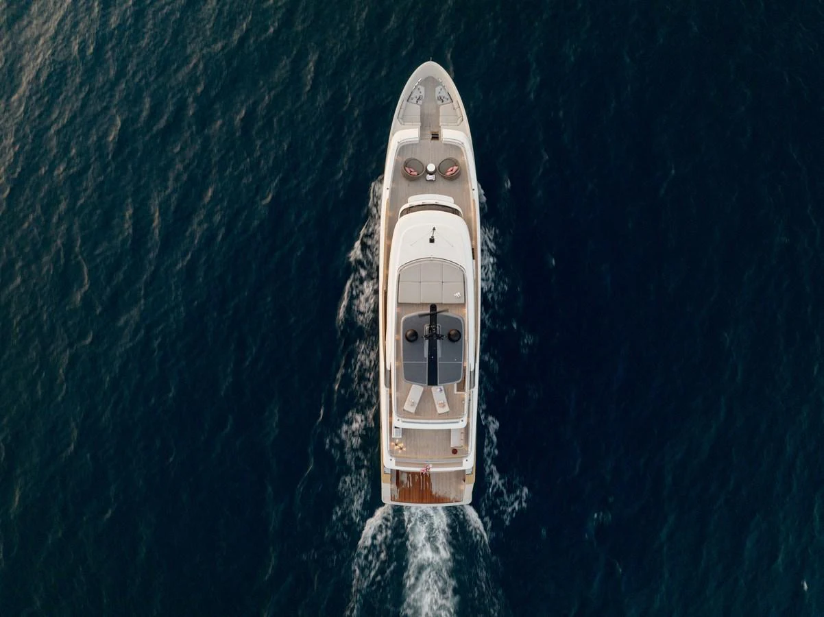 An aerial view of a luxurious yacht cruising through the water, showcasing its sleek design and spacious deck areas. aboard LET IT BE Yacht for Sale