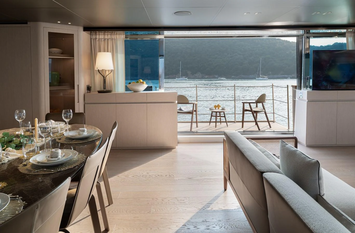 The salon offers a serene view of the water through large windows, complemented by elegant furnishings and a dining area. aboard LET IT BE Yacht for Sale