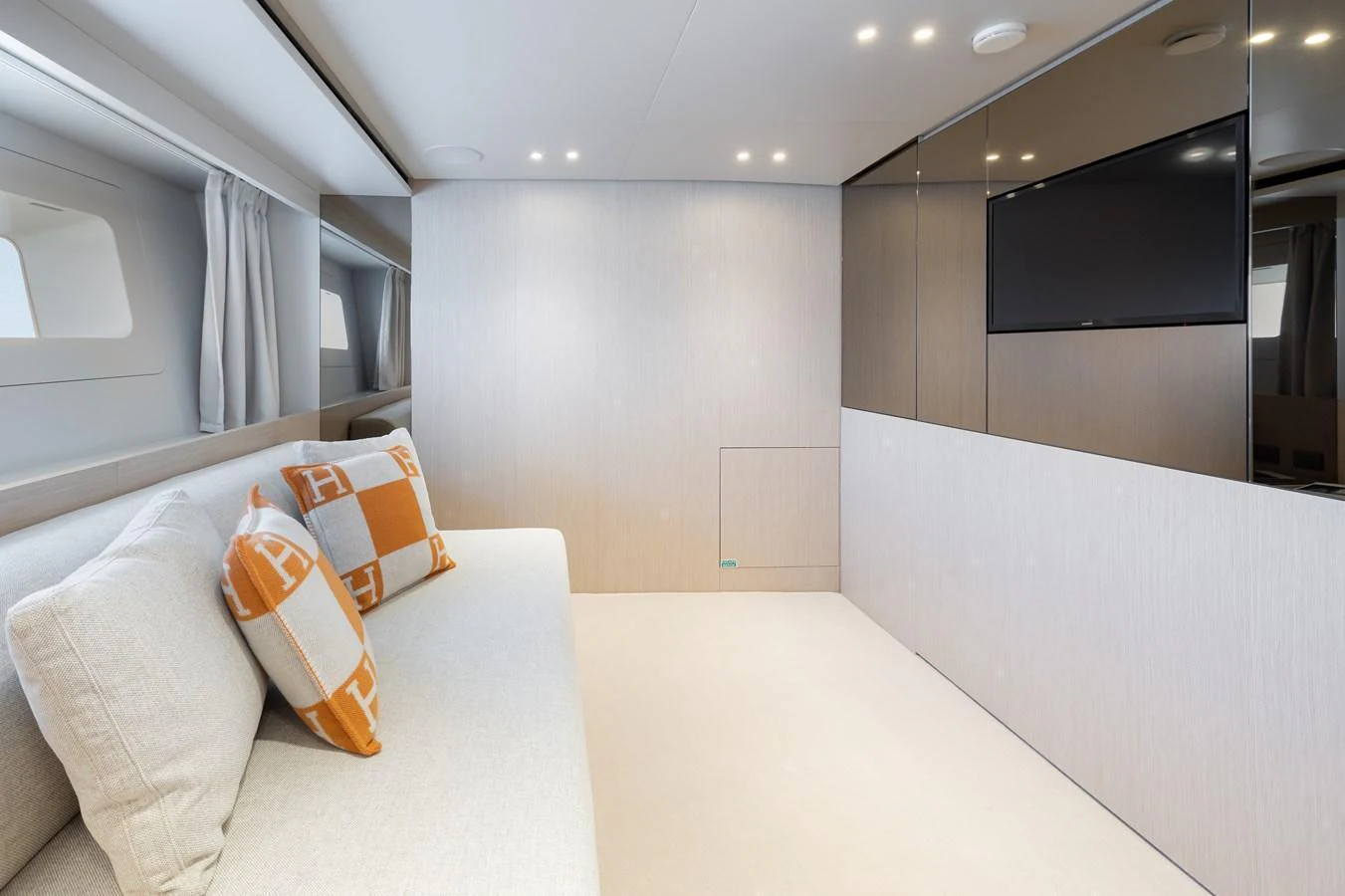 The salon features a modern and minimalist design with a comfortable sofa and a wall-mounted television. aboard LET IT BE Yacht for Sale