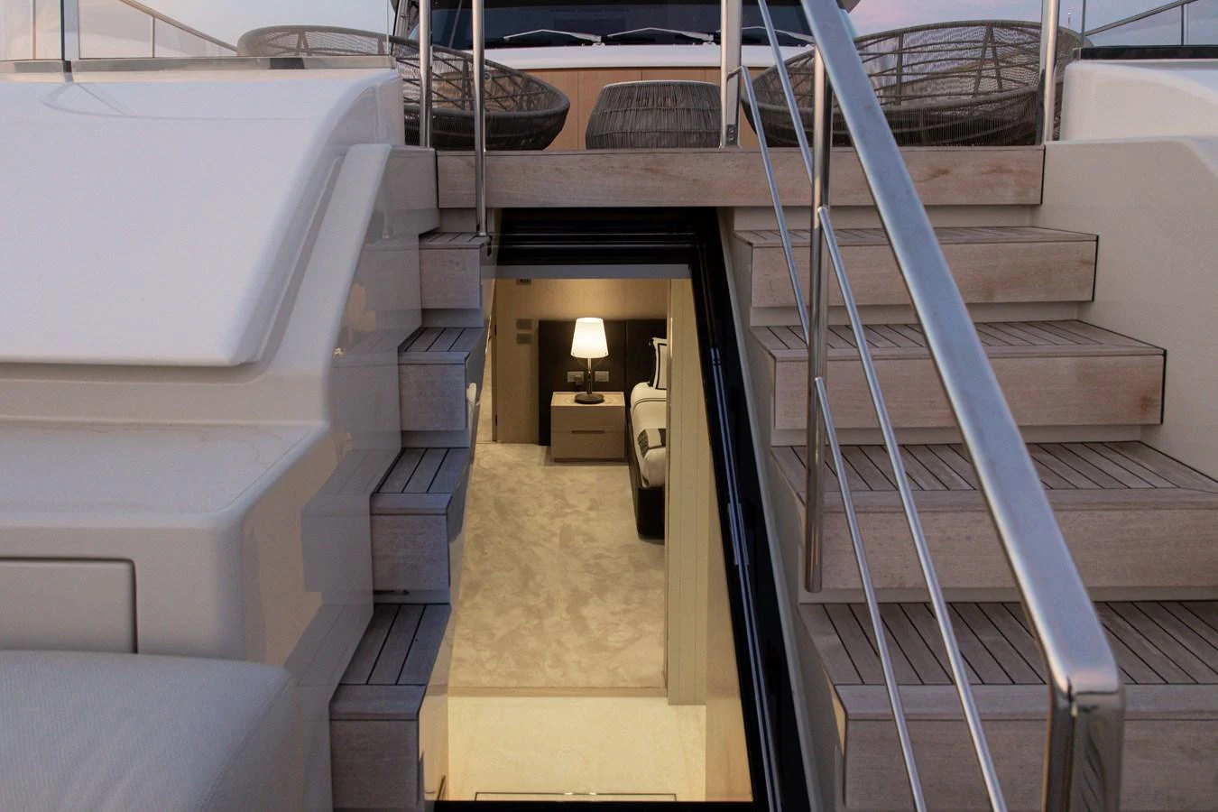 A luxurious stairway leading from the deck to the interior of the yacht, showcasing a glimpse of a cozy, well-lit room. aboard LET IT BE Yacht for Sale
