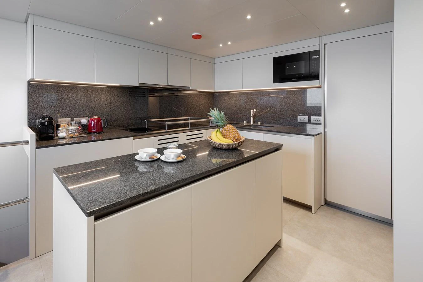 The modern galley features sleek cabinetry and a spacious island with a granite countertop. aboard LET IT BE Yacht for Sale