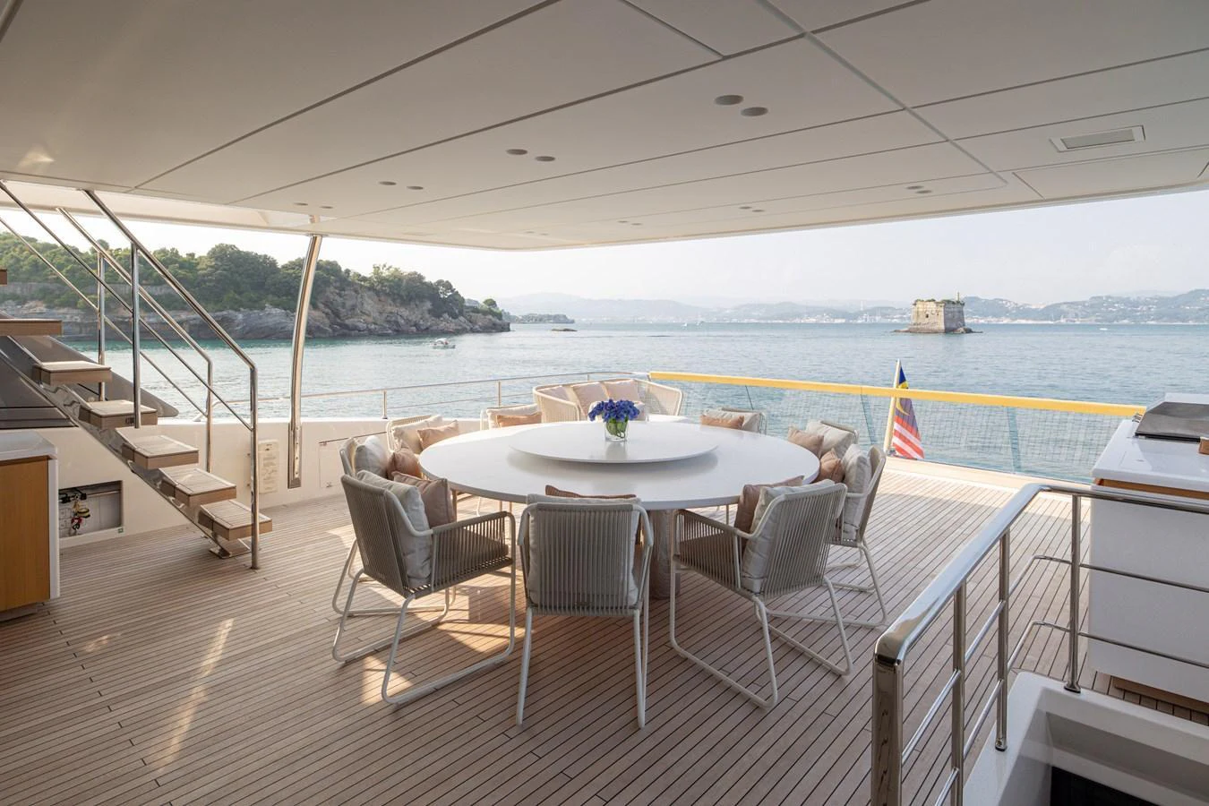 The aft deck features a spacious dining area with a round table and comfortable seating, perfect for enjoying meals with a view of the water. aboard LET IT BE Yacht for Sale