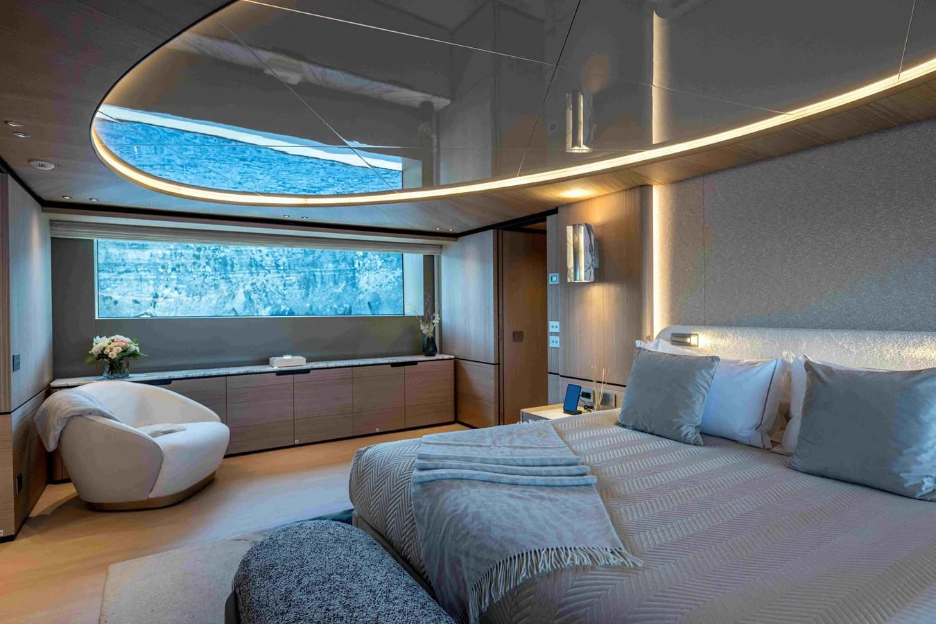 A luxurious stateroom featuring a large bed, modern furnishings, and a panoramic window with a scenic view. aboard UNIQUE S Yacht for Sale