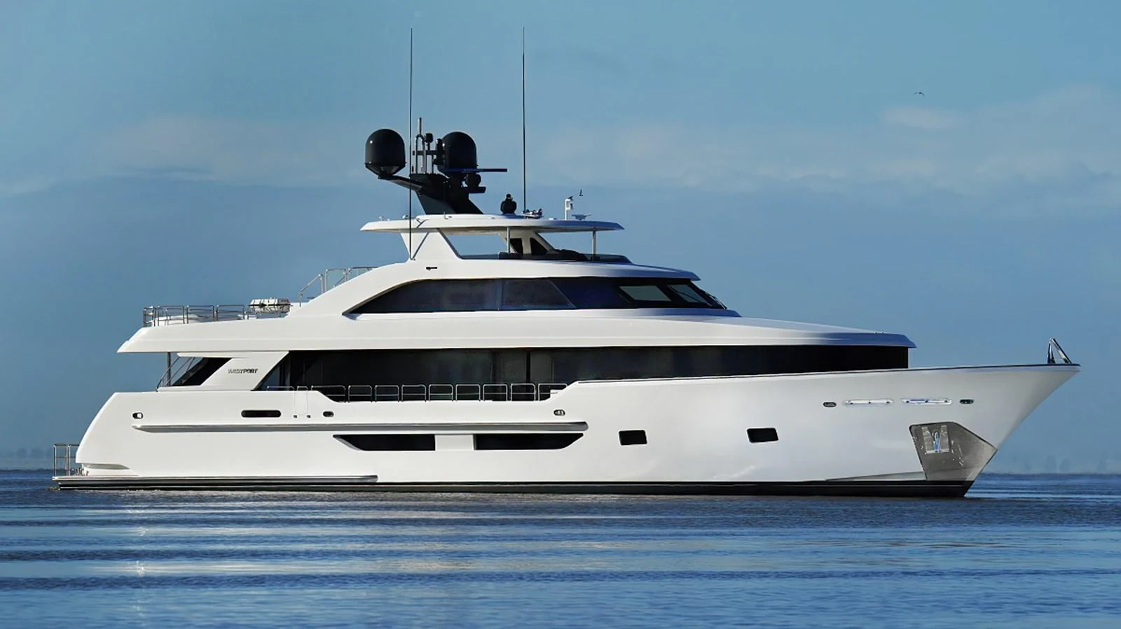 A sleek and modern yacht glides gracefully on calm waters under a clear sky. aboard WESTPORT 117 / 35M Yacht for Sale