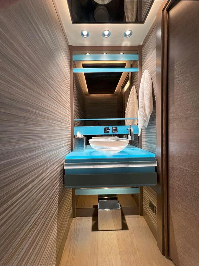A sleek and modern yacht bathroom with elegant wood paneling and a stylish vessel sink. aboard WESTPORT 117 / 35M Yacht for Sale
