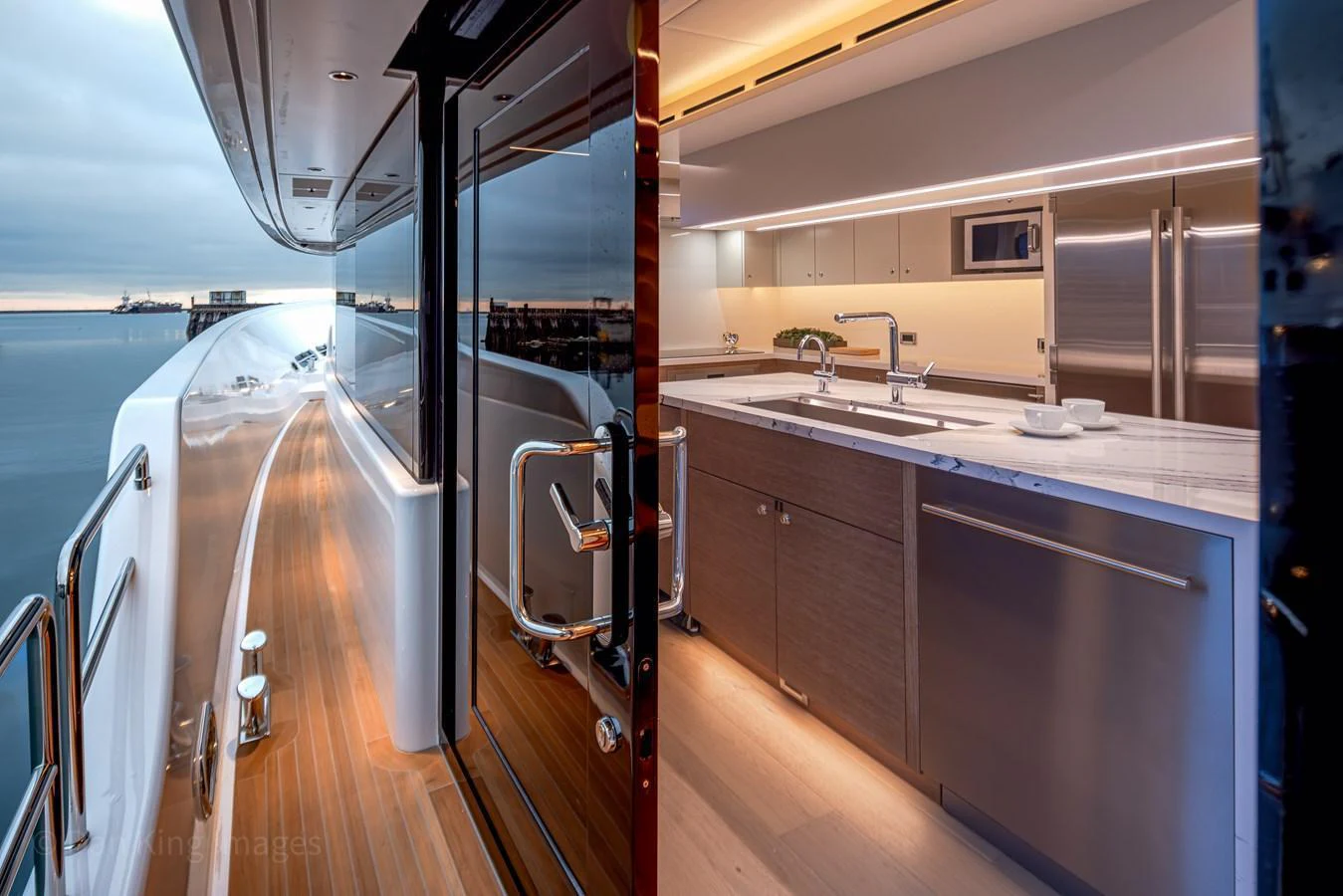 The modern galley features sleek cabinetry and high-end appliances, seamlessly blending with the yacht's exterior walkway. aboard WESTPORT 117 / 35M Yacht for Sale