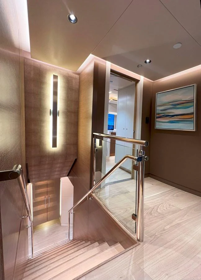 A beautifully designed staircase with modern lighting and artwork, leading to the lower deck. aboard WESTPORT 117 / 35M Yacht for Sale