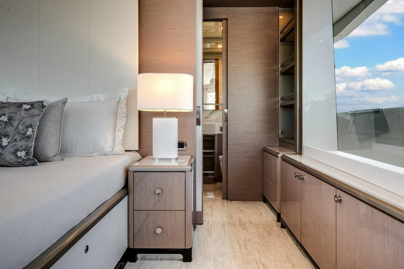 The stateroom features a cozy bed, a stylish nightstand with a lamp, and ample natural light from the large window. aboard OCEAN ALEXANDER 37L Yacht for Sale