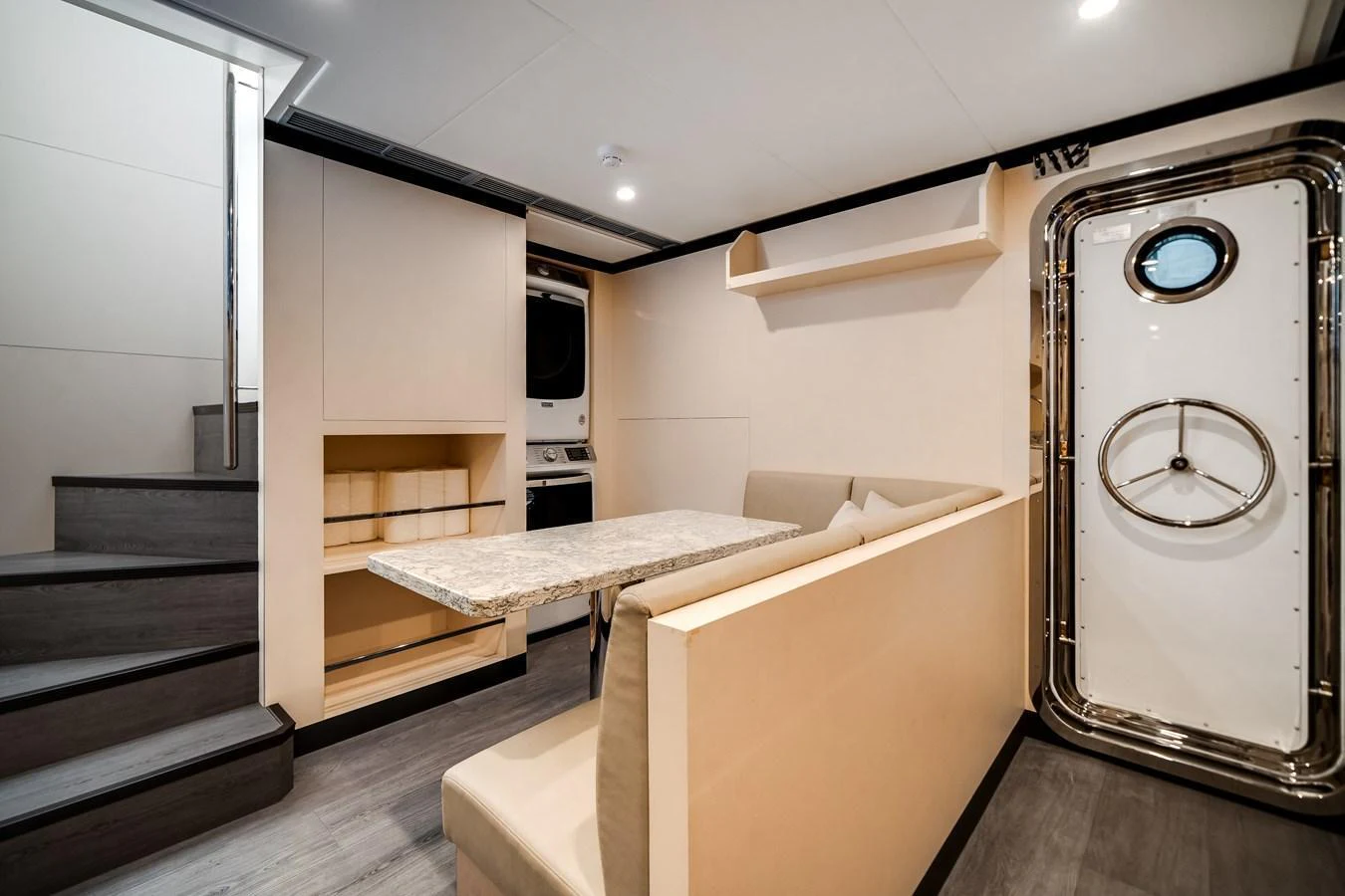 The yacht's interior features a cozy dining area with a table and bench seating, adjacent to a staircase and a secure door. aboard OCEAN ALEXANDER 37L Yacht for Sale