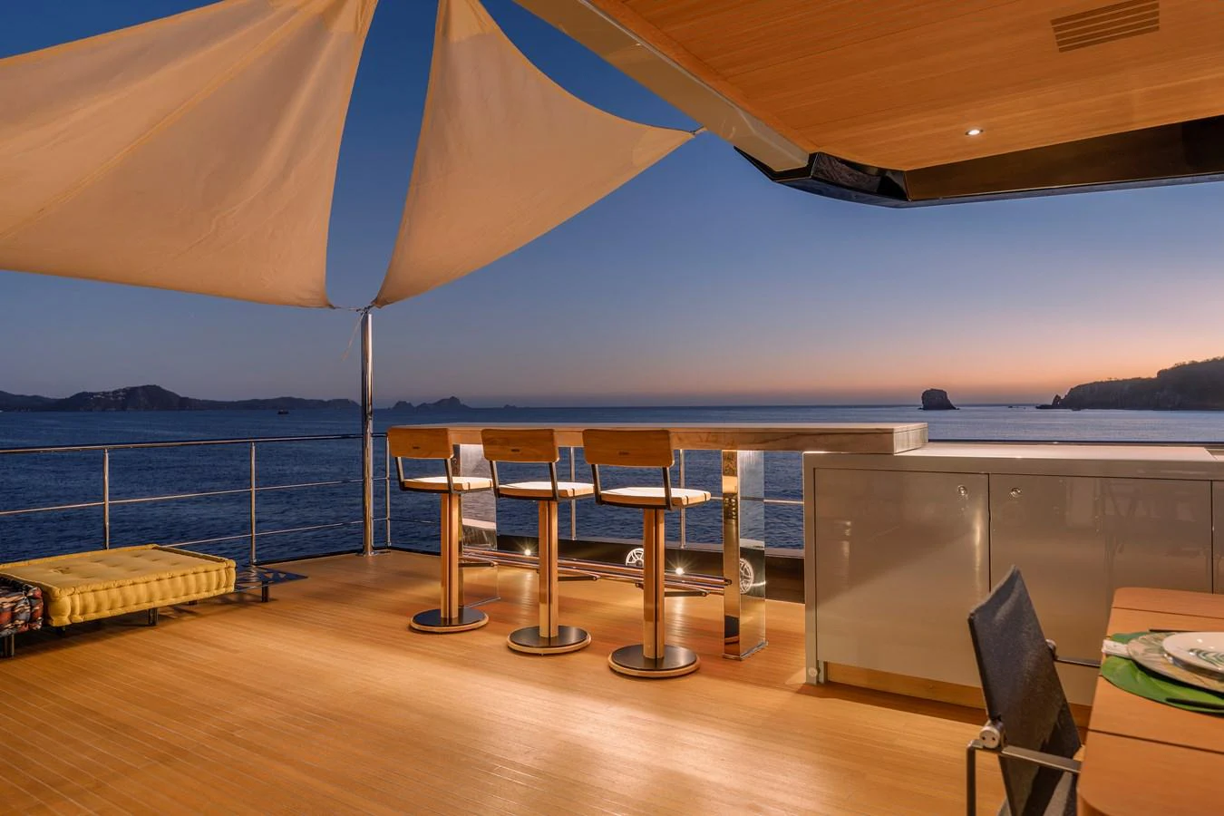 The aft deck offers a serene setting with bar stools and a canopy, perfect for enjoying the sunset over the water. aboard SPRITZ 116 Yacht for Sale