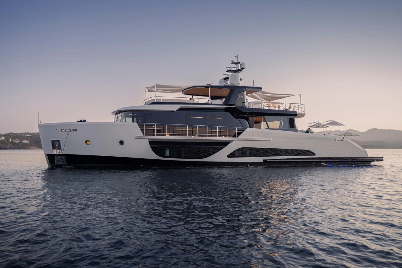 A sleek and modern yacht glides gracefully on calm waters during sunset. aboard SPRITZ 116 Yacht for Sale