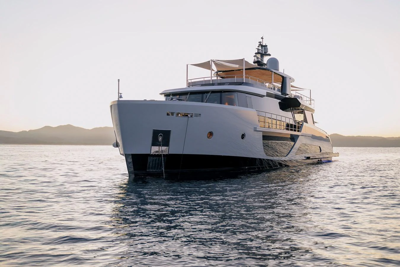 A sleek and modern yacht glides gracefully on calm waters at sunset. aboard SPRITZ 116 Yacht for Sale