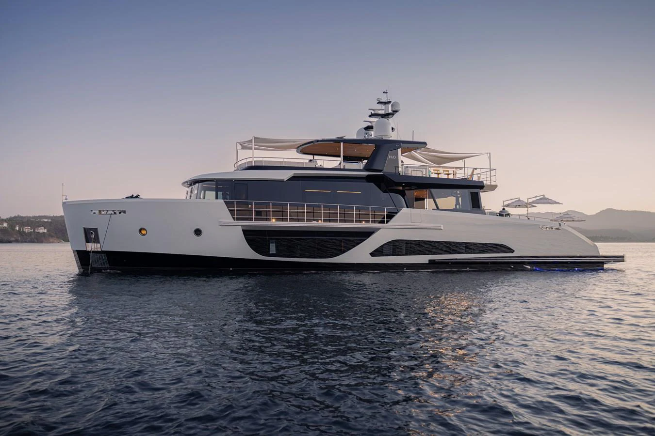 A sleek and modern yacht is anchored on calm waters during sunset. aboard SPRITZ 116 Yacht for Sale