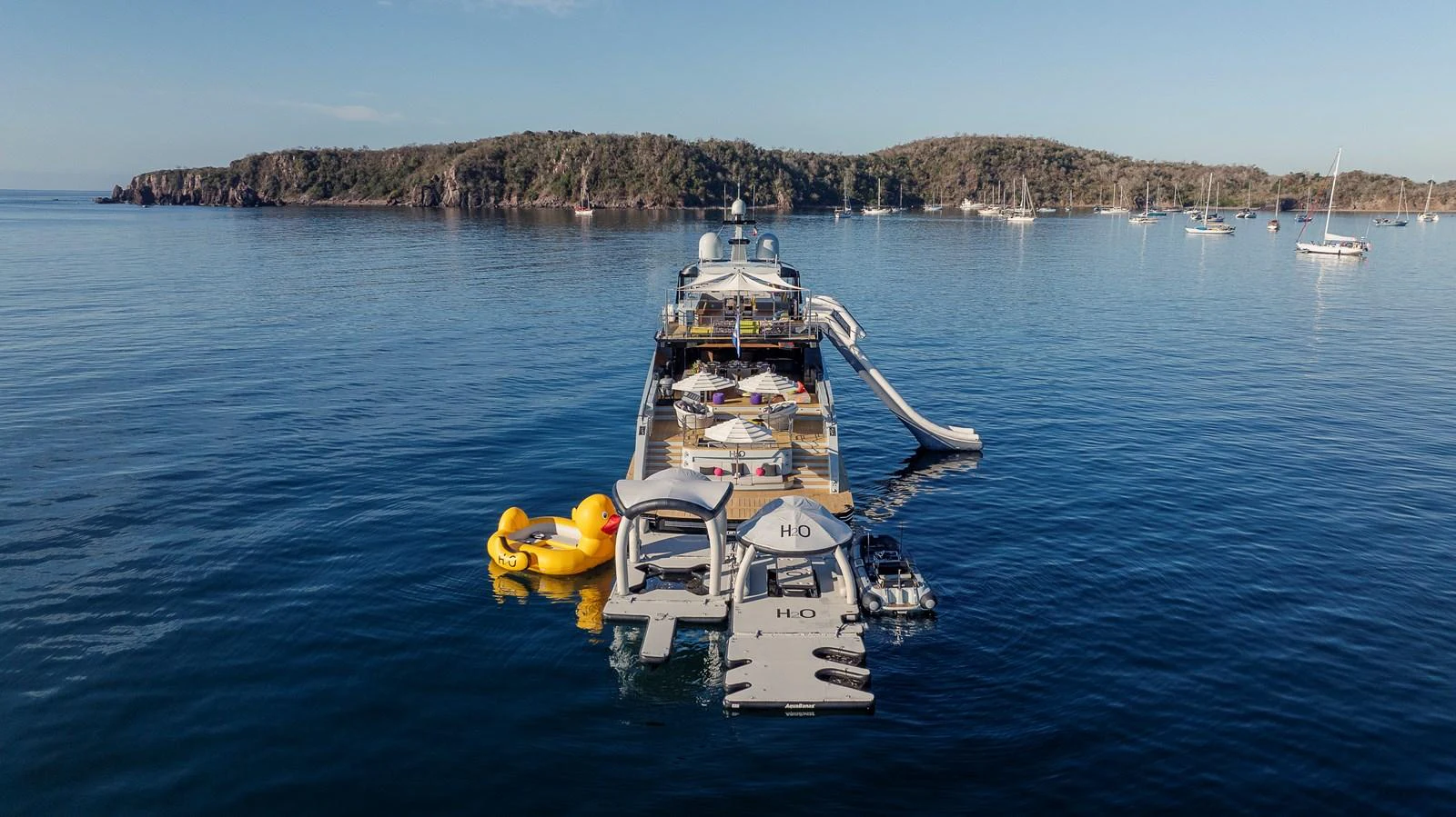 A luxurious yacht anchored in a serene bay, featuring an array of water toys and a slide for ultimate enjoyment. aboard H2O - SPRITZ 116 Yacht for Sale