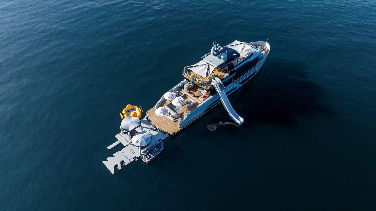 The yacht's aft deck features an array of water toys and a slide, perfect for ocean fun. aboard H2O - SPRITZ 116 Yacht for Sale