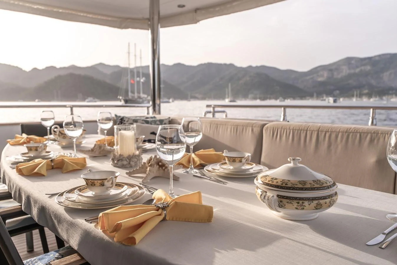 An elegant alfresco dining setup on the yacht's deck, offering a picturesque view of the surrounding mountains and sea. aboard JAFE TICA Yacht for Sale