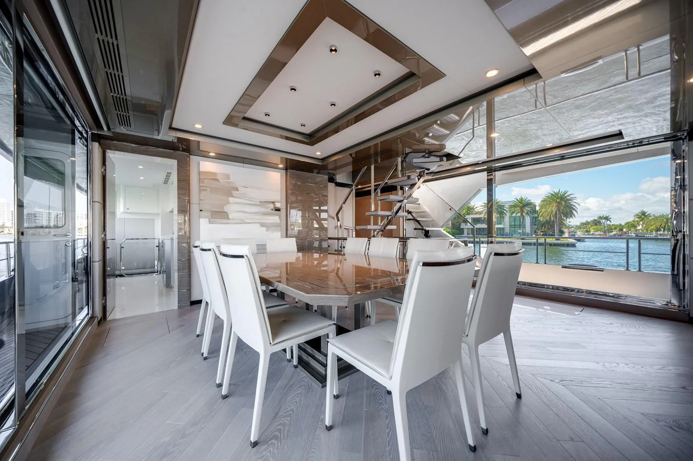 The yacht's dining area features a modern design with a large table and white chairs, offering a luxurious setting with a view of the water. aboard OCEAN ALEXANDER 44G/01 Yacht for Sale