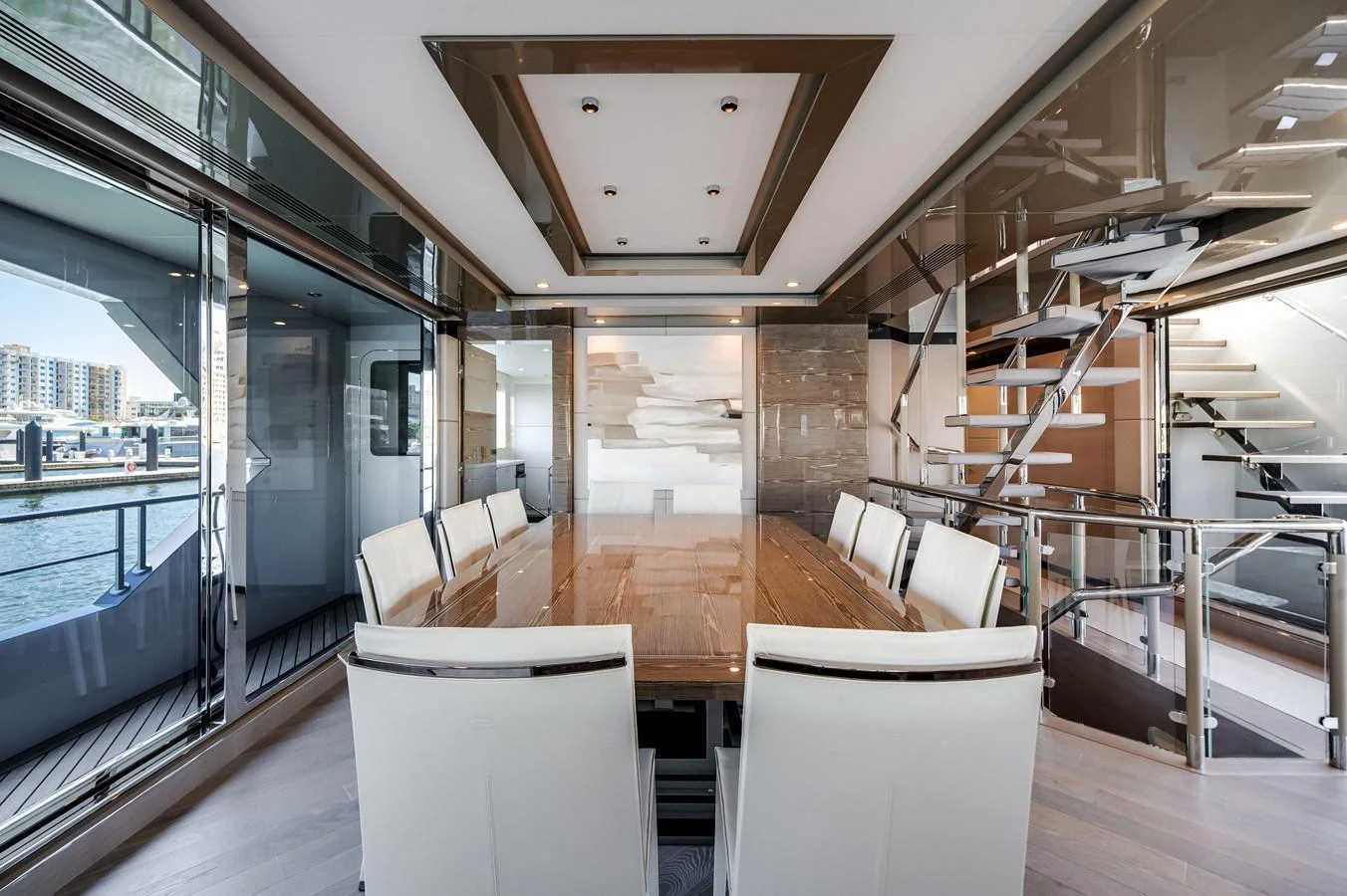 The yacht's dining area features a sleek, modern design with a large wooden table and white upholstered chairs, surrounded by expansive windows offering stunning views. aboard OCEAN ALEXANDER 44G/01 Yacht for Sale