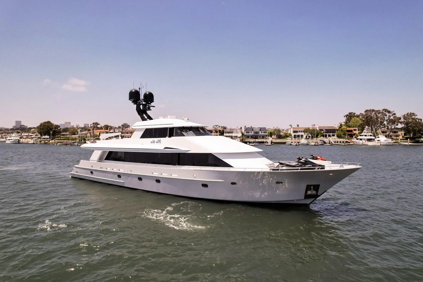 A sleek, modern yacht cruises through calm waters with a scenic shoreline in the background. aboard GOLDEN BOY II Yacht for Sale