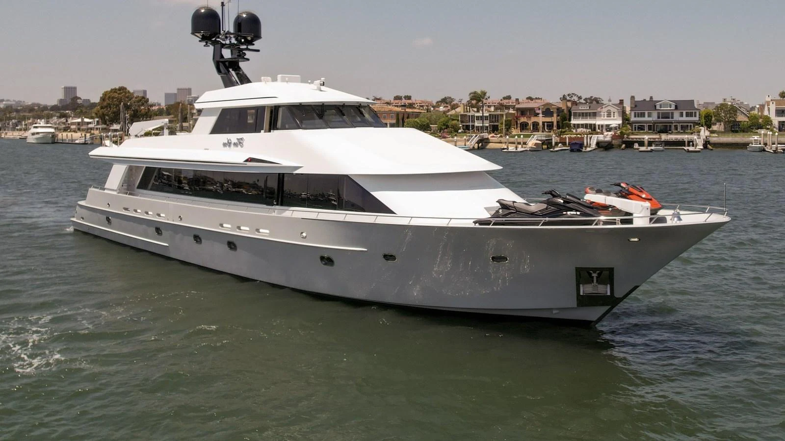 A sleek and modern yacht cruising on calm waters with a cityscape in the background. aboard GOLDEN BOY II Yacht for Sale