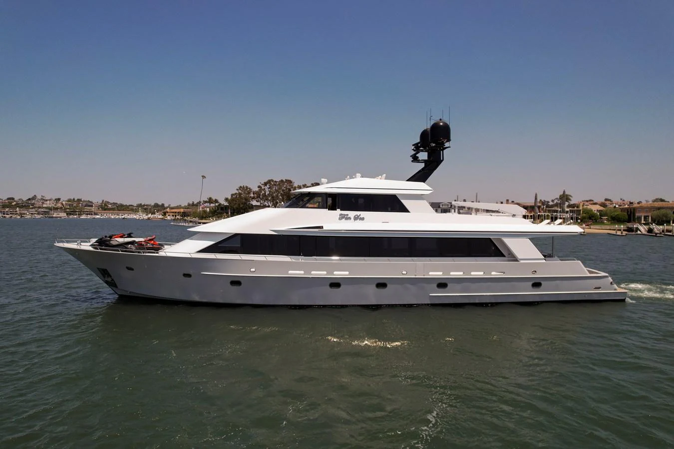 A sleek yacht cruises on calm waters near a coastal town. aboard GOLDEN BOY II Yacht for Sale